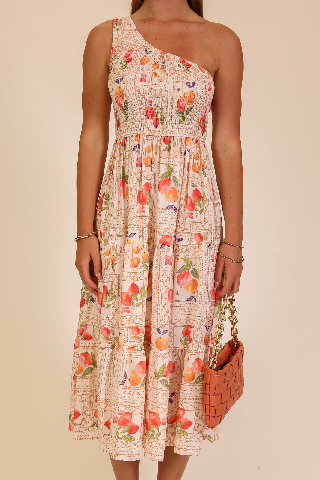 Woman wearing a floral one-shoulder dress with a beige background